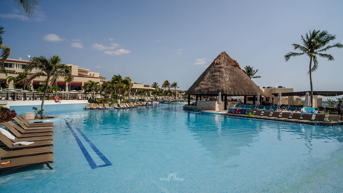 Alberca principal de Moon Palace Cancún con bar de palapa y camastros