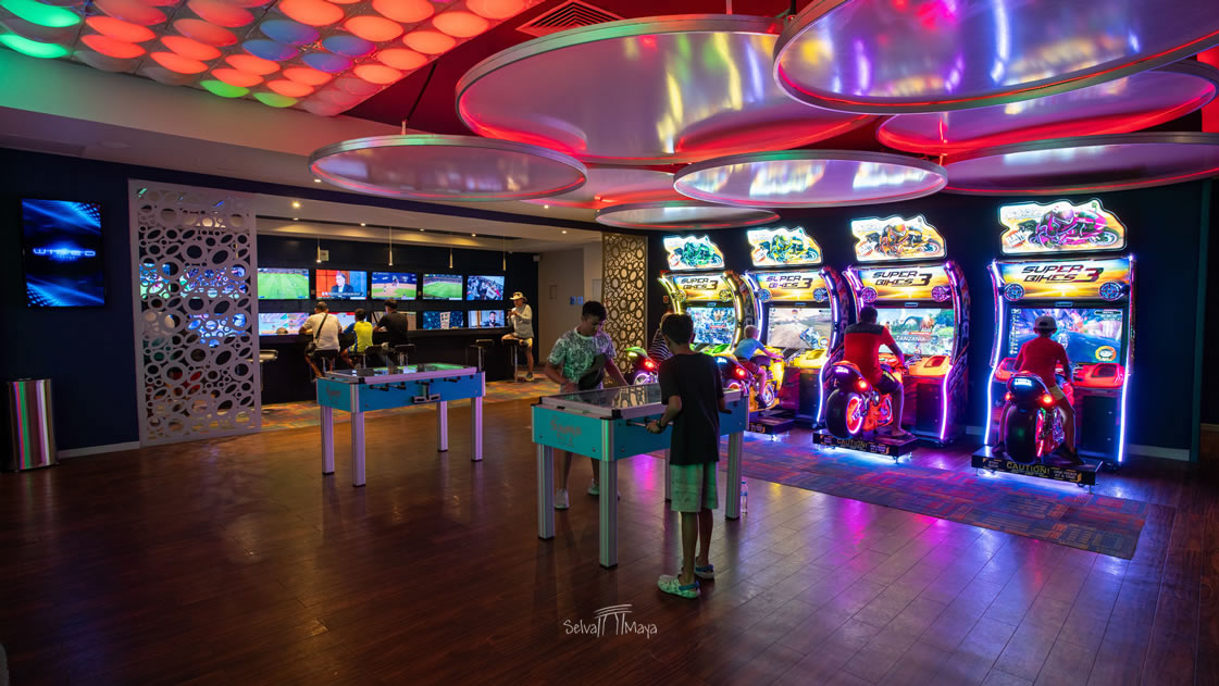 Sala de arcade de Moon Palace Cancún con máquinas de videojuegos, futbolito y air hockey