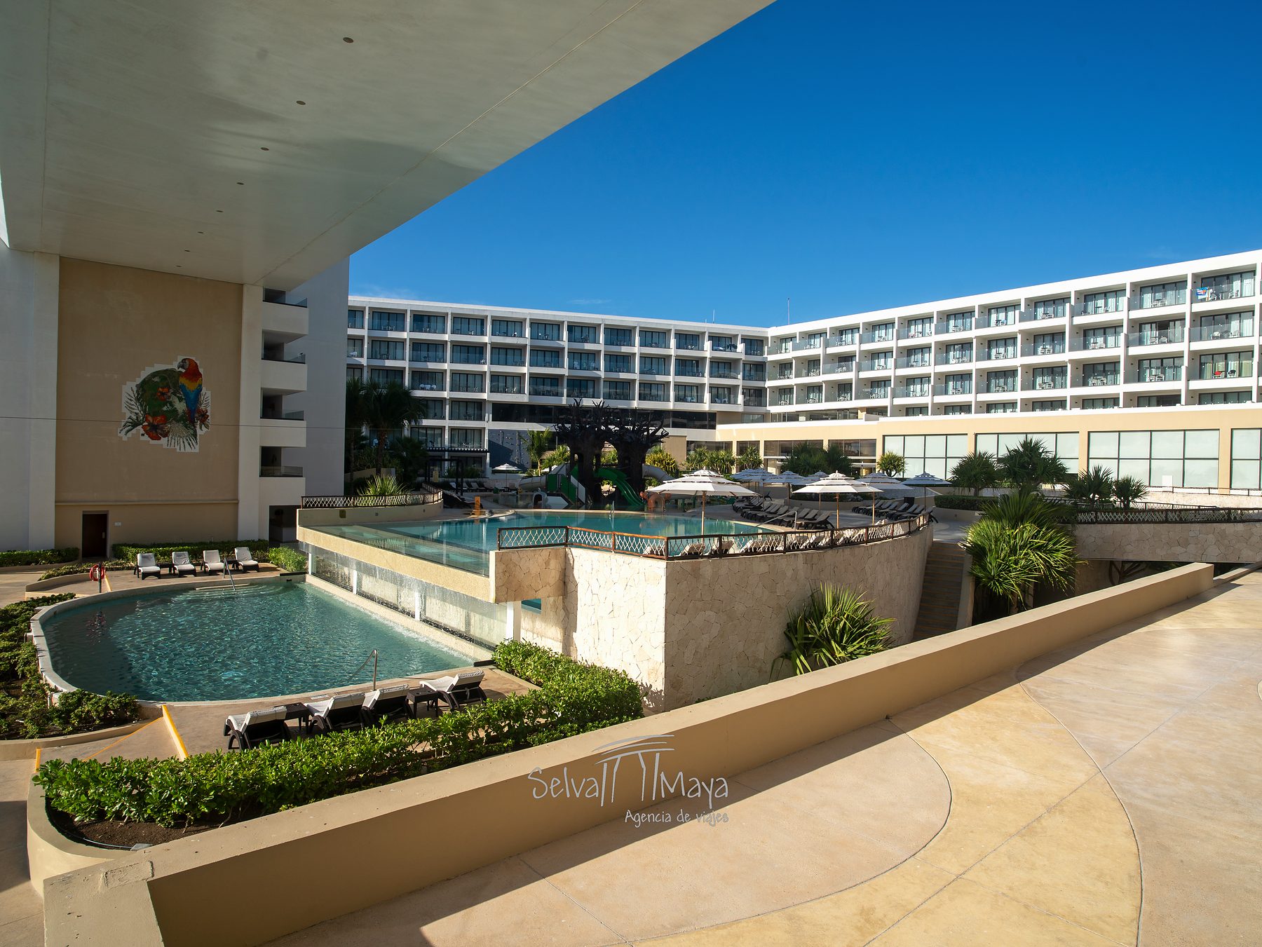 Albercas a distintos niveles y edificio en Sensira Resort Riviera Maya
