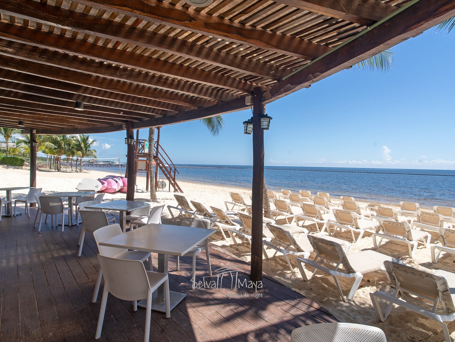 Mesas bajo pérgola con vista a la playa en Sensira Resort Riviera Maya
