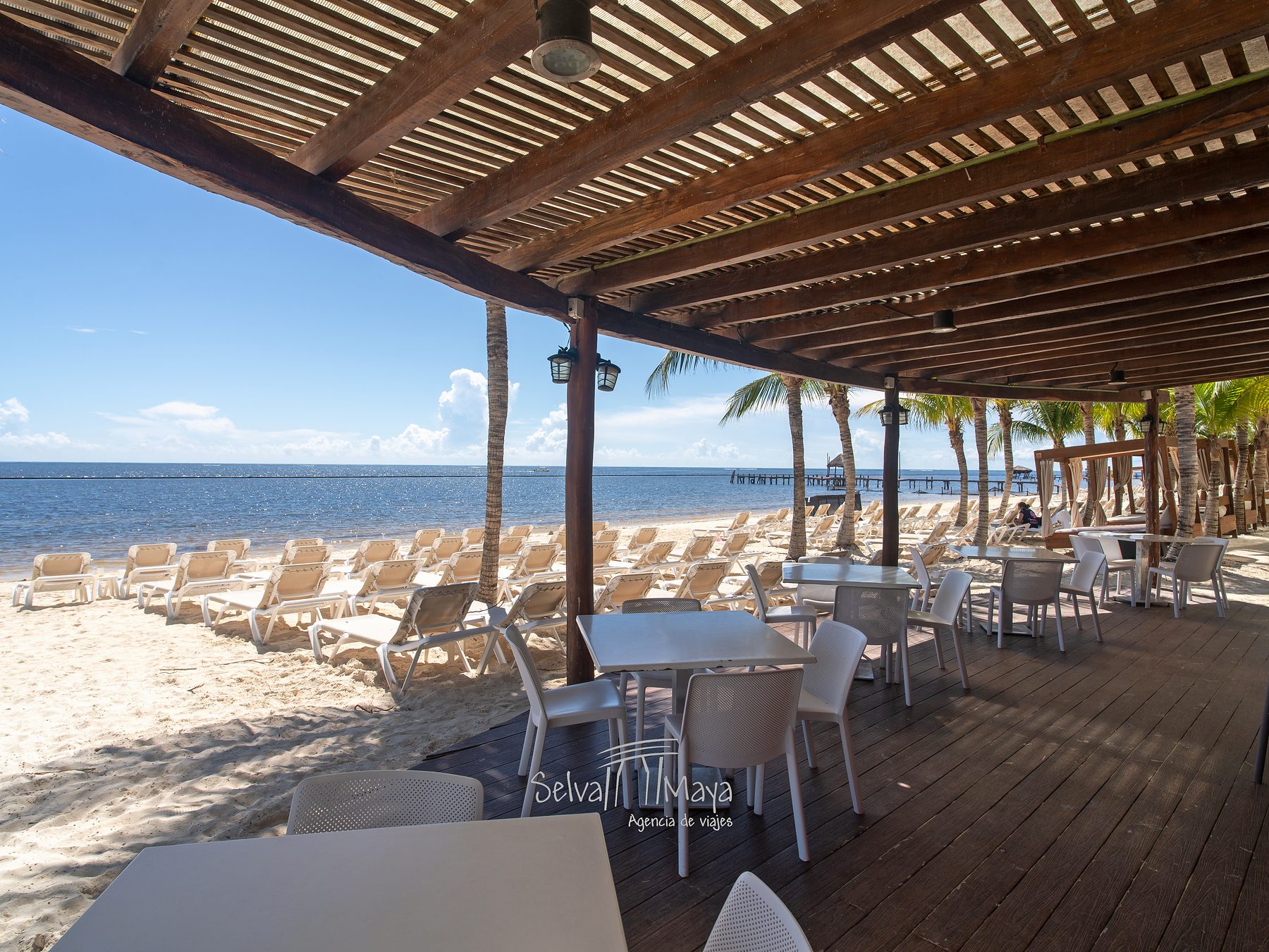 Pérgola de madera con mesas frente al mar en Sensira Resort Riviera Maya