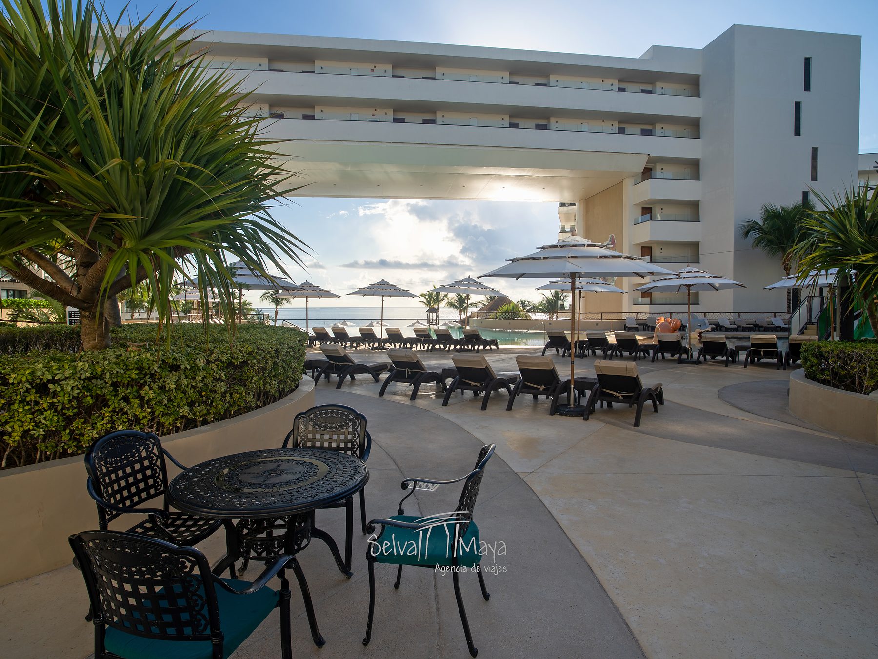 Terraza con mesas frente a la alberca en Sensira Resort Riviera Maya