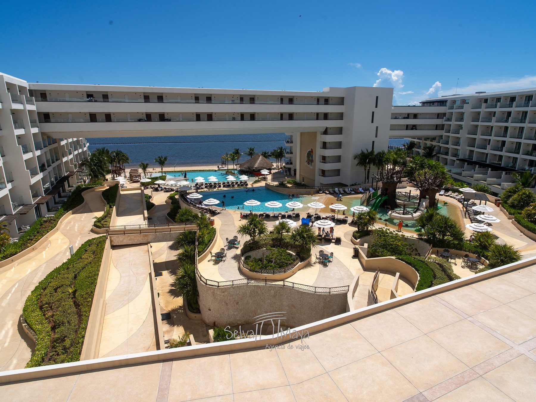Vista elevada de jardines y edificio hacia el mar en Sensira Resort Riviera Maya