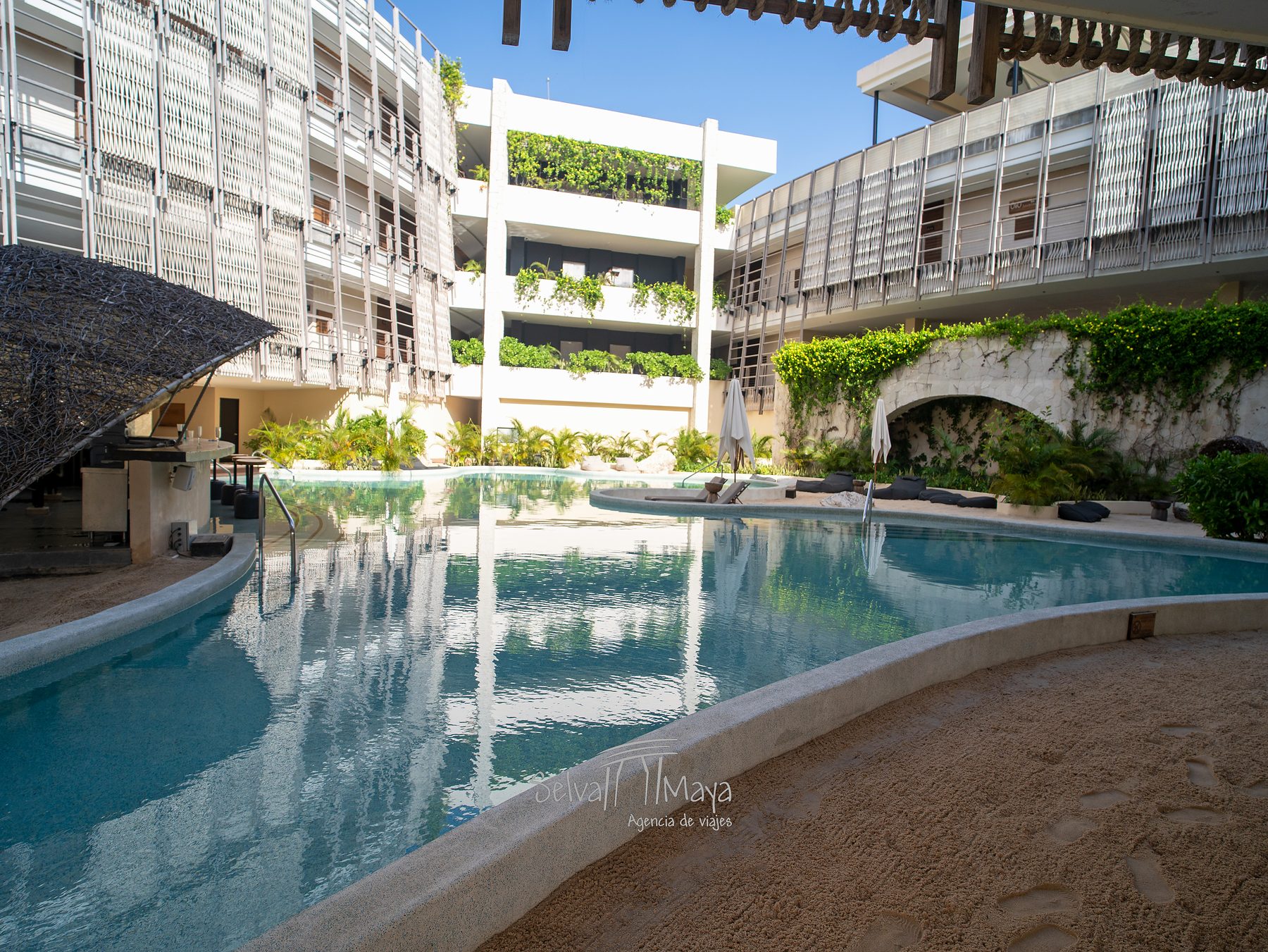 Alberca entre edificios con jardines verticales en Secrets Tulum