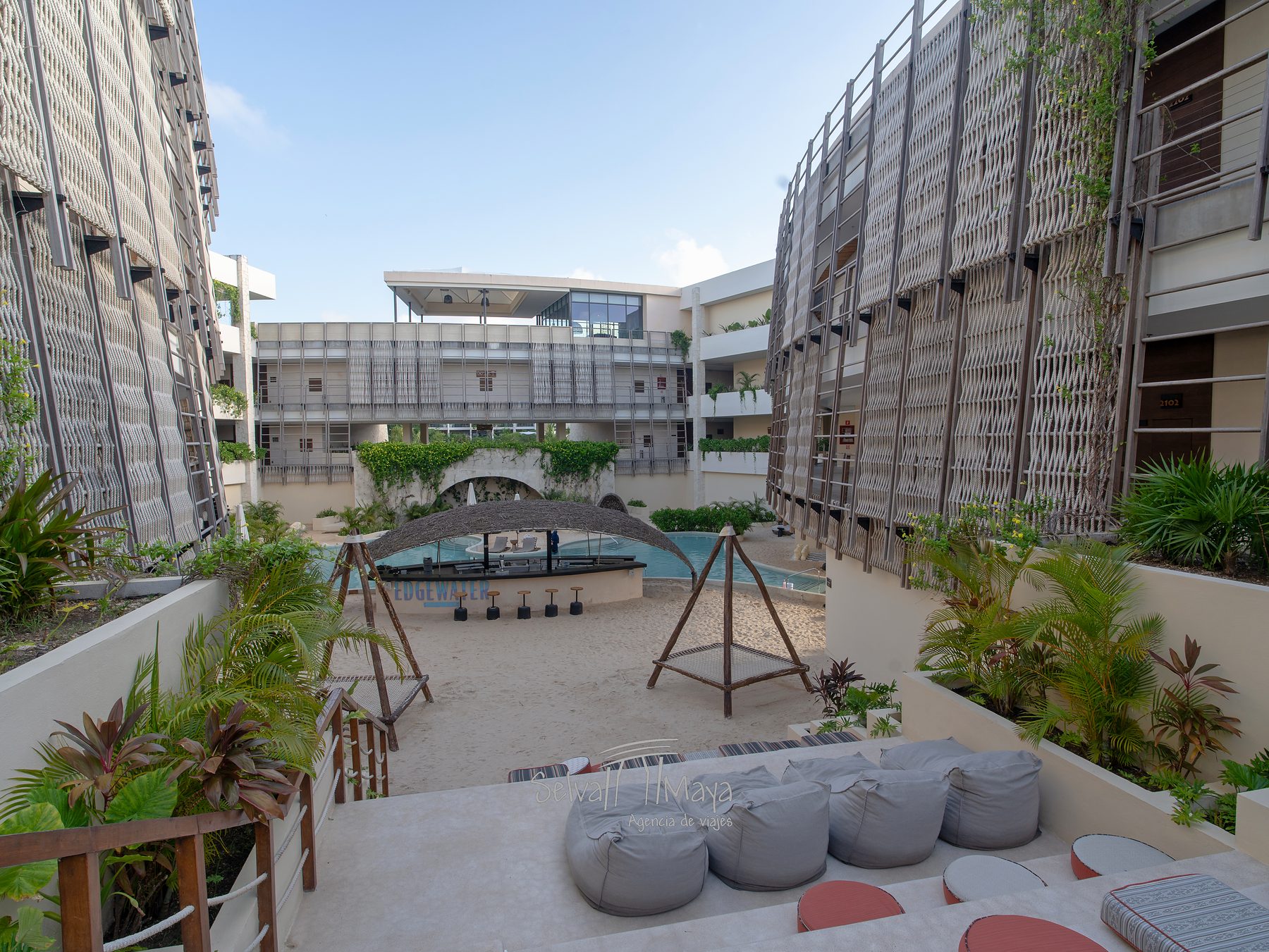 Zona de descanso con puffs y camas colgantes en Secrets Tulum